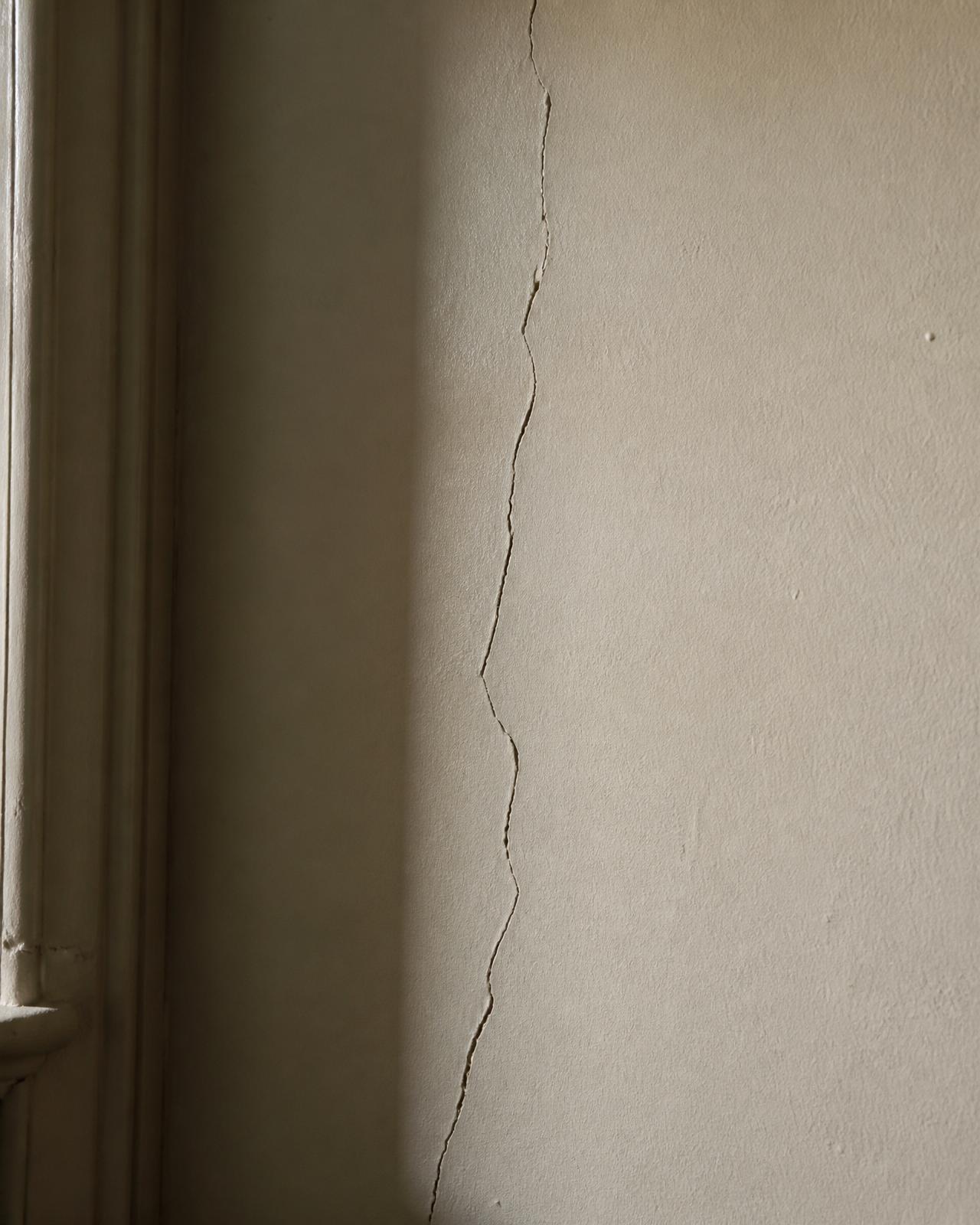 Hairline crack, plaster wall by doorframe